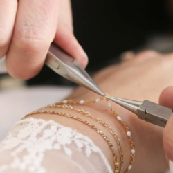 Permanent jewellery bracelet being attached with precision pliers during a professional jewellery training session.