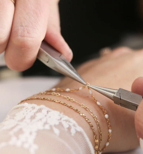 Permanent jewellery bracelet being attached with precision pliers during a professional jewellery training session.